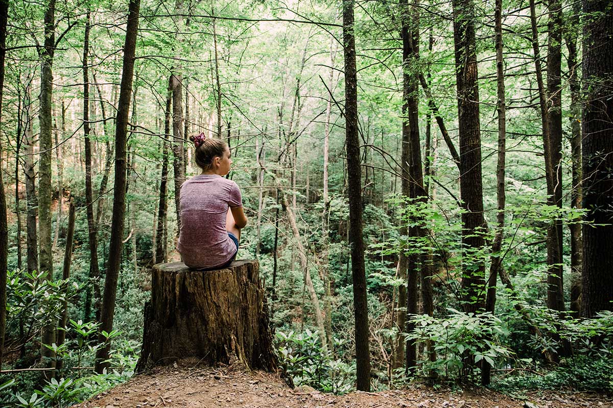 woman sitting during hike in the woods