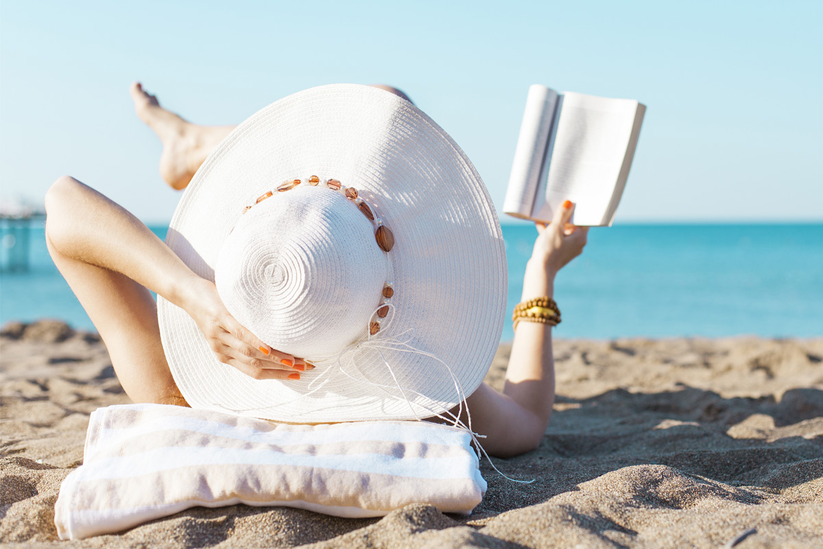 woman reading book on beach