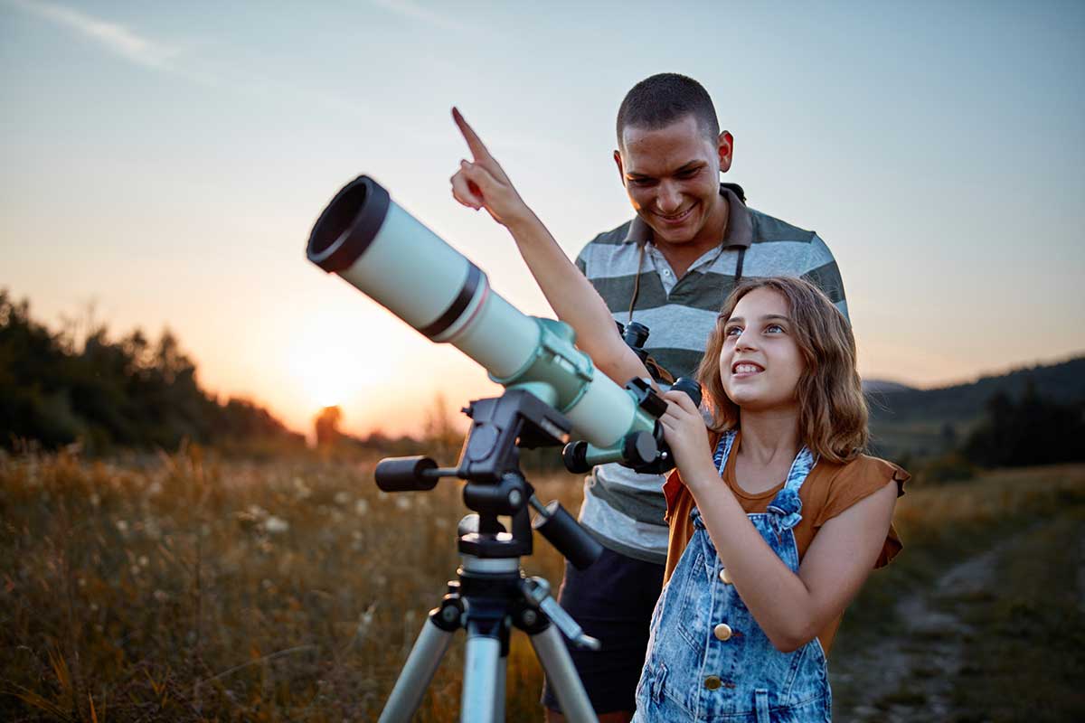 dad and daughter looking through telescope