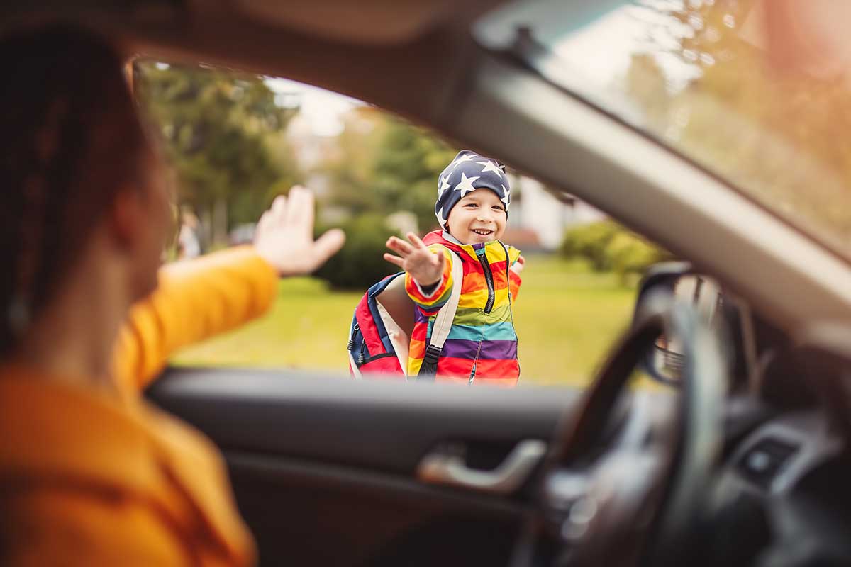 child waving to parent in car