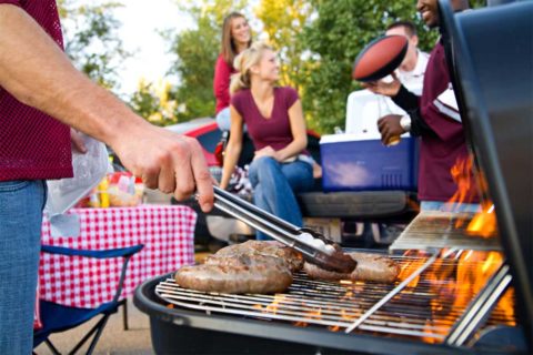 man grilling sausages at barbecue or tailgate