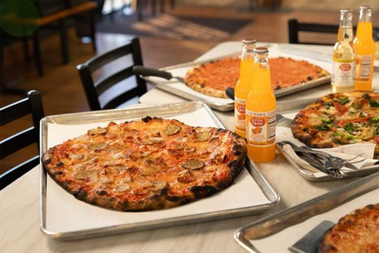frank pepe pizza on a table with drinks