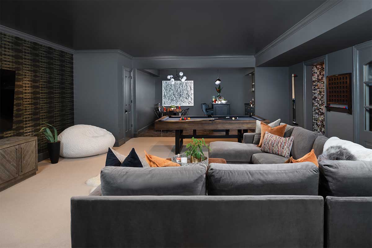 dark colored living room with sectional and pool table