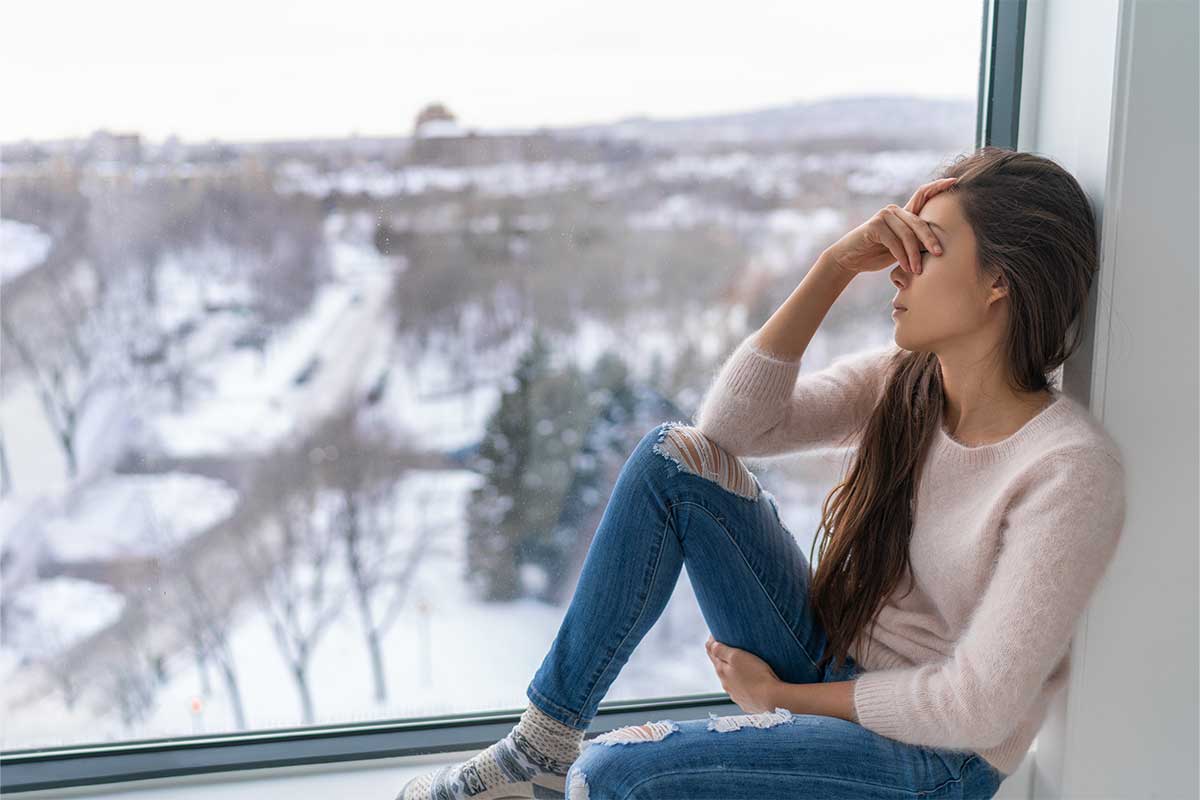 woman sitting by window during winter