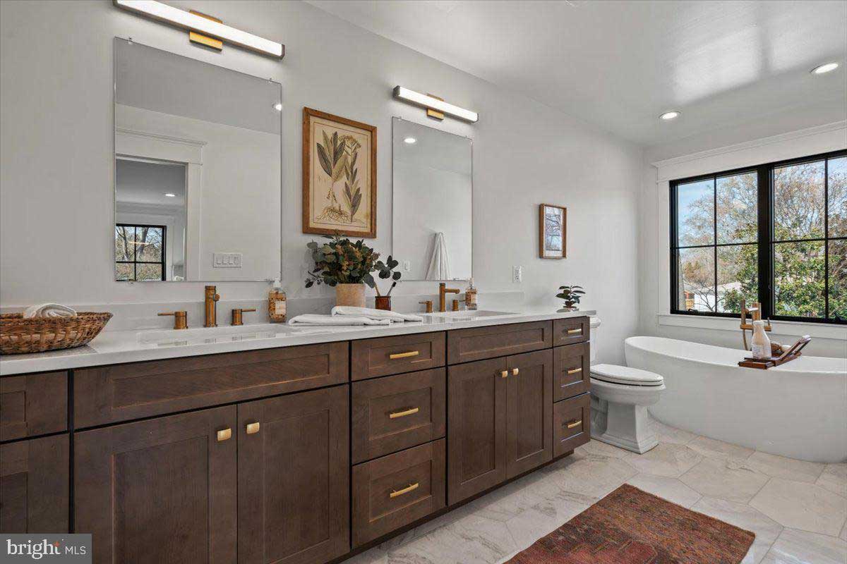 white bathroom with dark cabinets and standalone tub