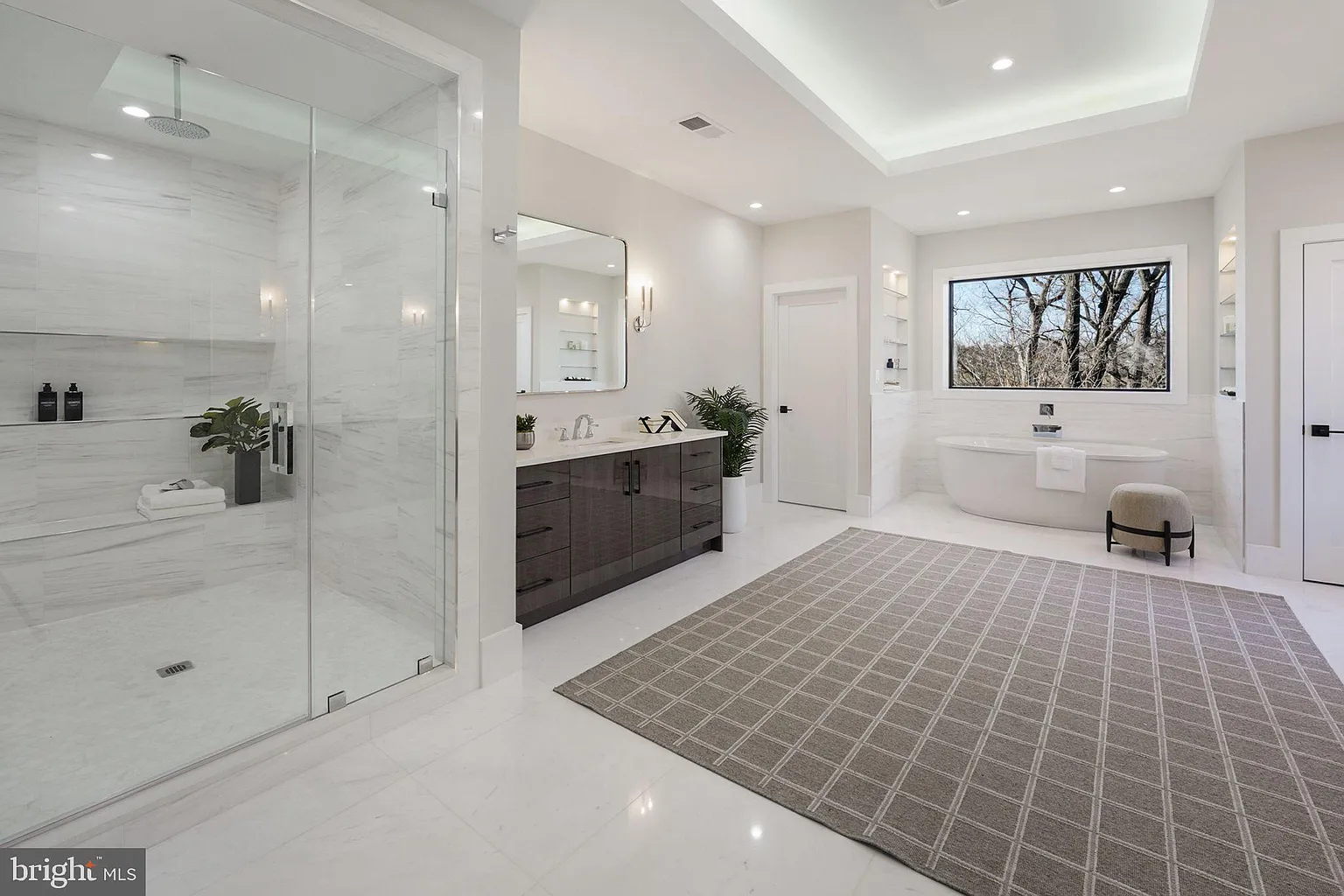 view of home's primary bathroom with glass doored shower and spa bath under bathroom window