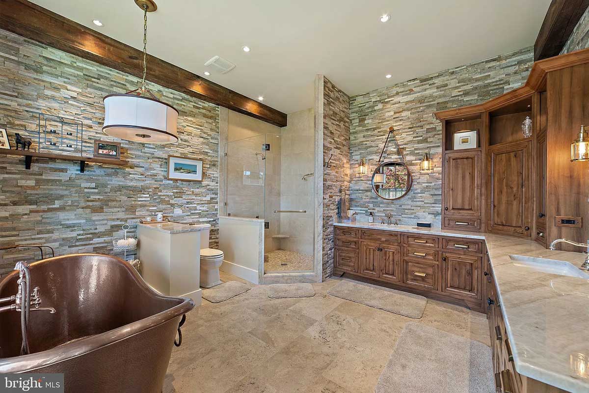 primary bathroom with stone walls and copper soaking tub