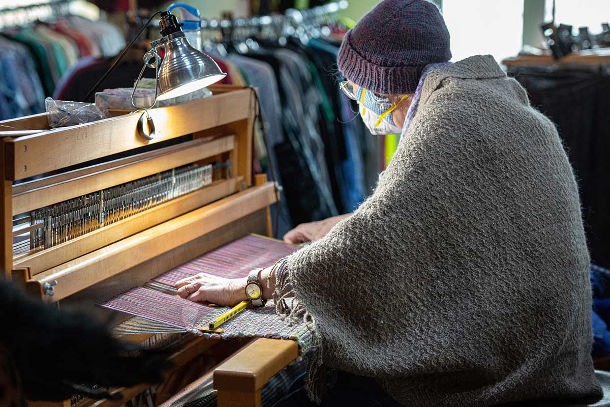 A guest weaves on the thrift store's community loom