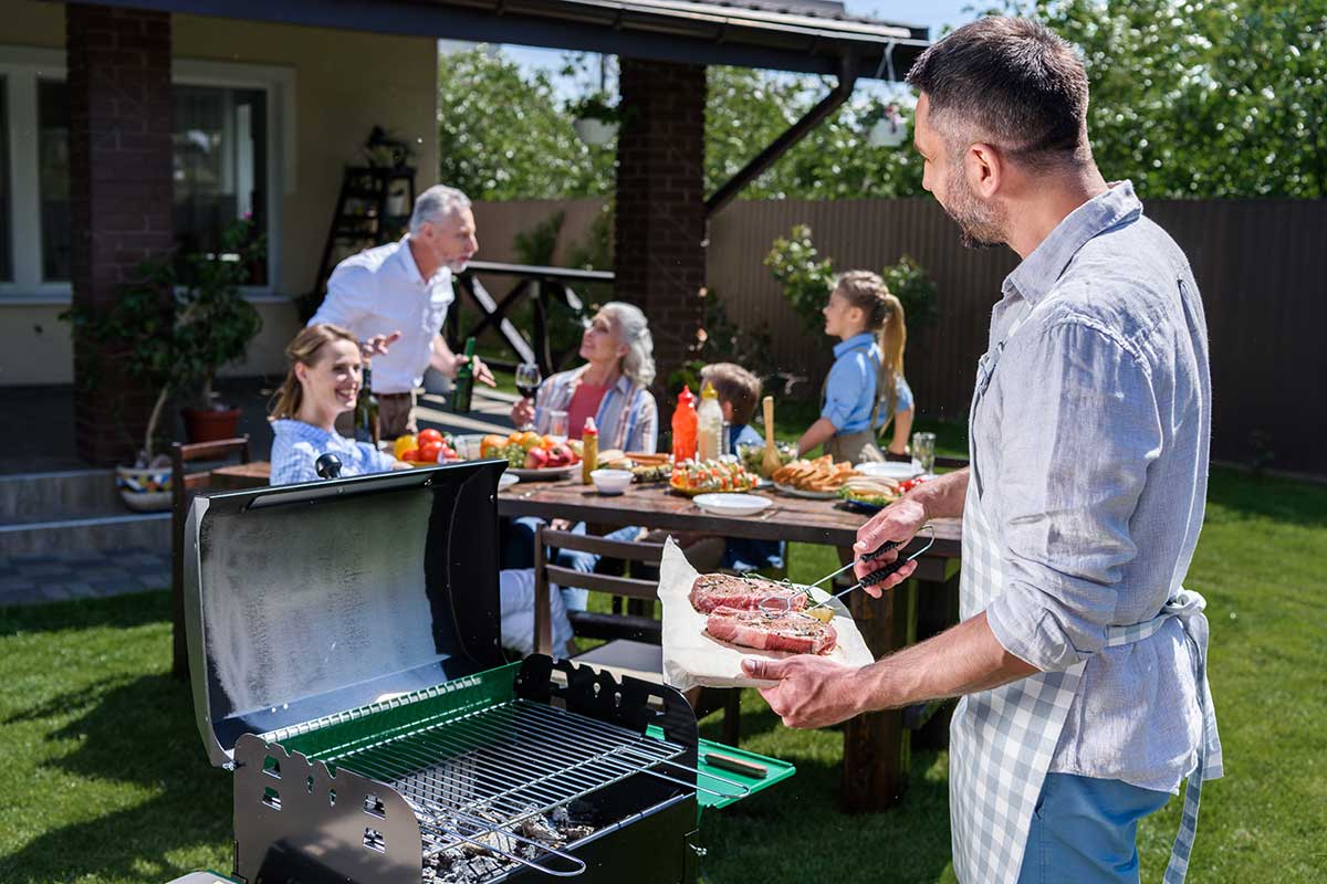 man at a grill with family in the background