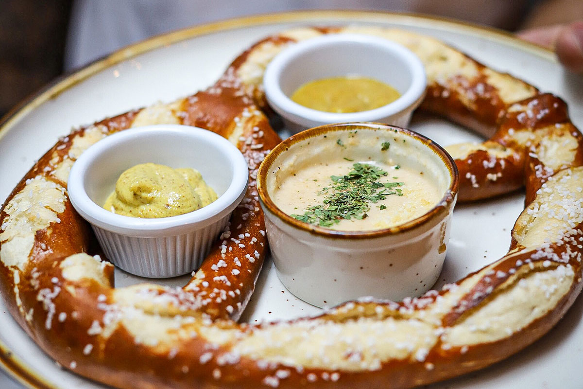 Large pub pretzel with mustard and cheese sauce