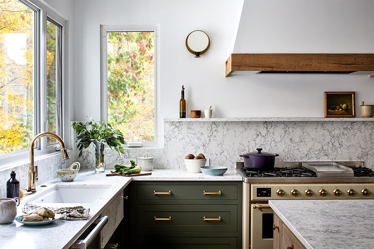 A kitchen area with white countertops, bronze hardware, and green cabinets