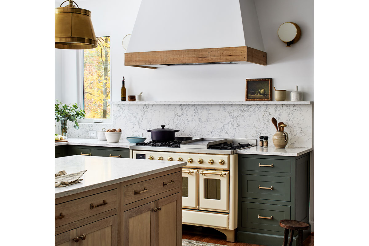 A kitchen island with light wood and a white marble top. Behind it, a cream-colored oven and white backsplash.