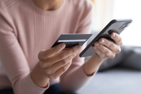 Person holding a cell phone and a credit card