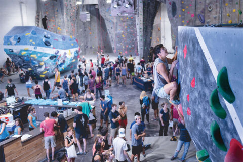 Person climbing rock wall at indoor climbing studio