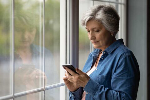 woman at window using cellphone