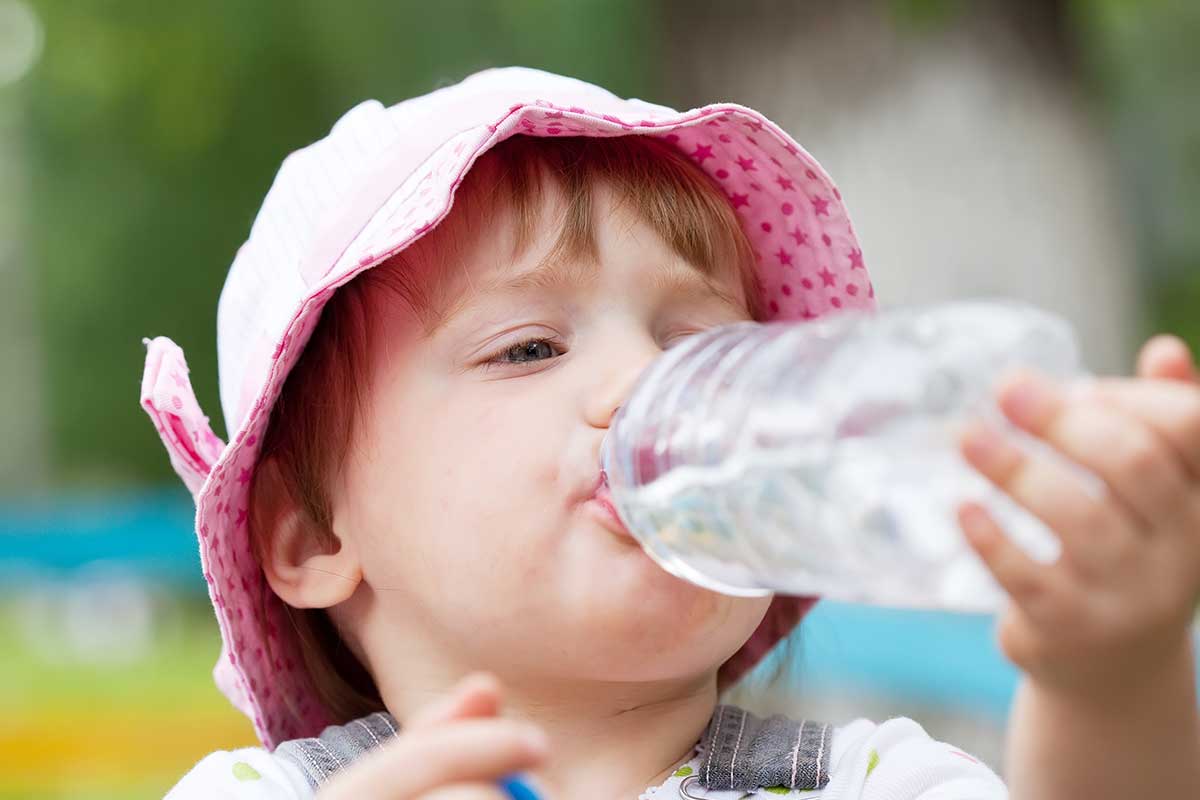 child wearing a hat drinking from water bottle