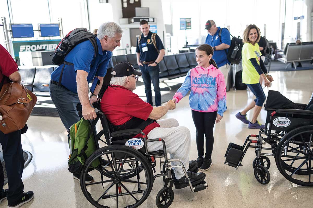 veteran in wheelchair shaking girls hand