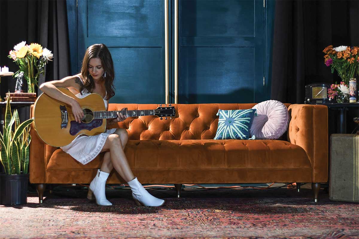 Karen Jones playing guitar on couch