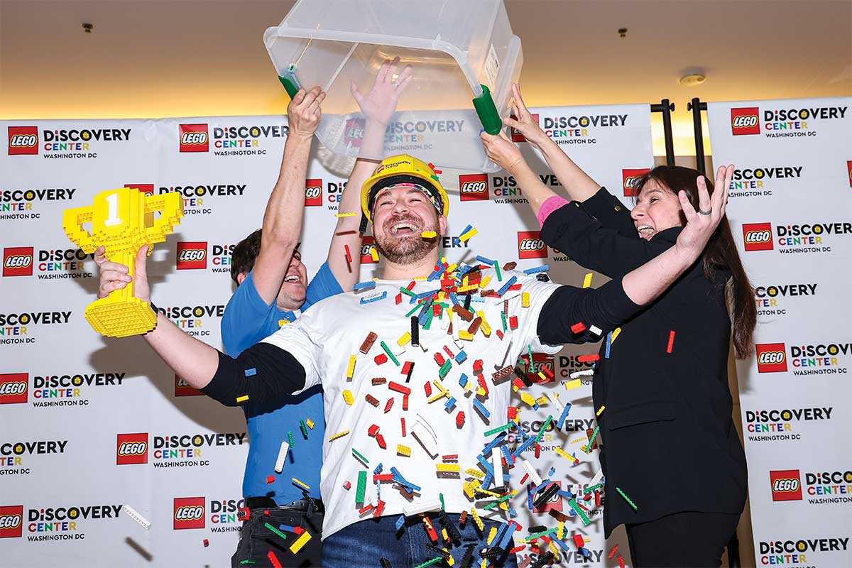 Andrew Litterst surrounded by Legos, holding a Lego trophy