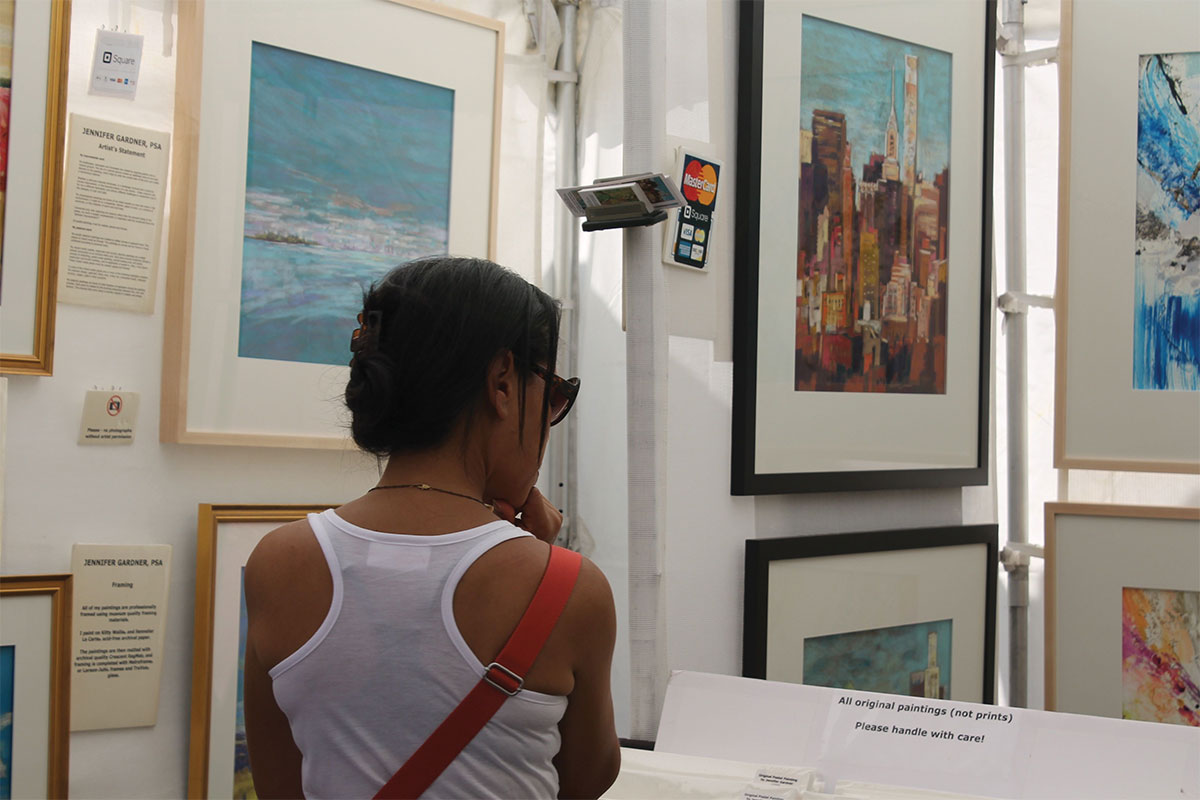 Woman looking at paintings at Alexandria Art Festival