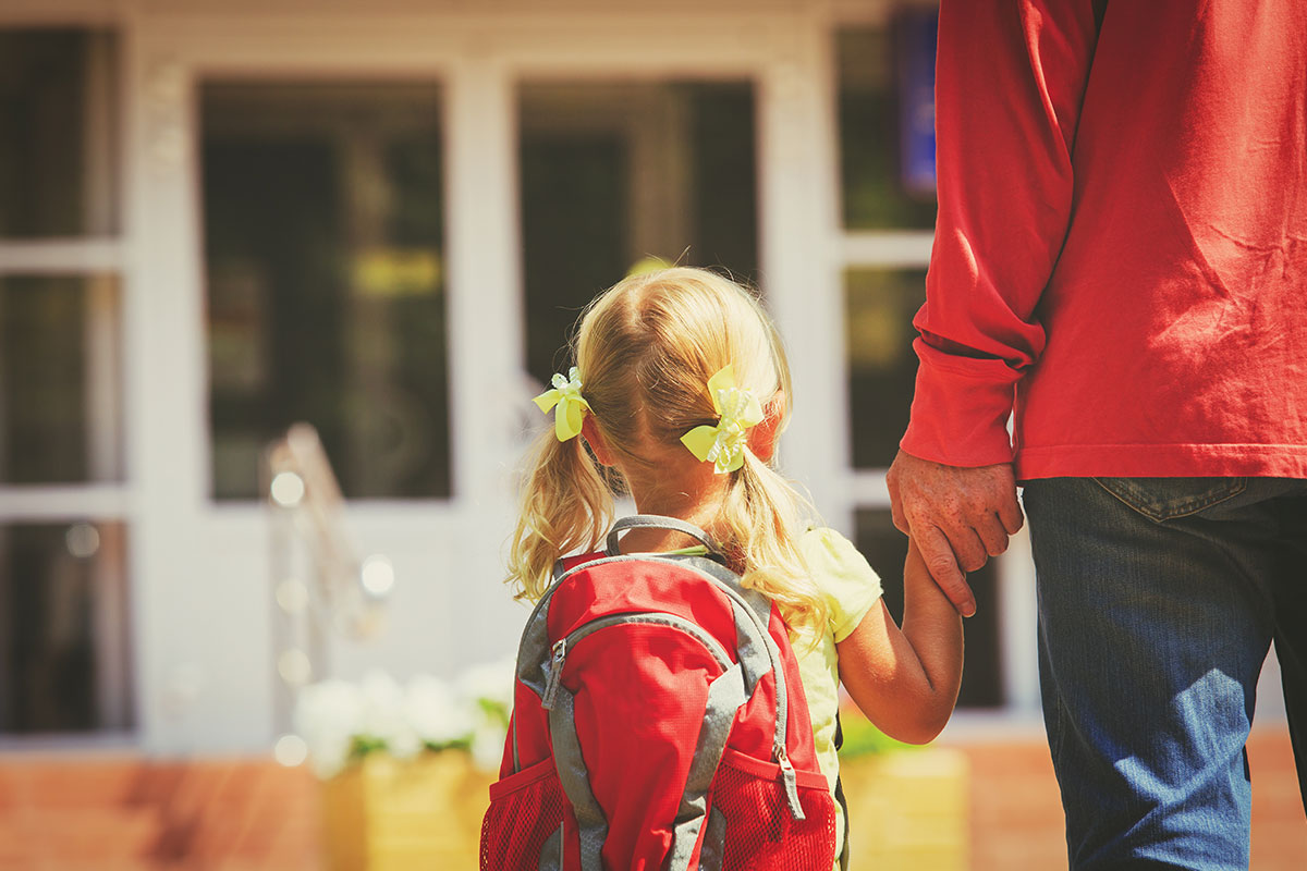 Girl with backpack holding her dad's hand