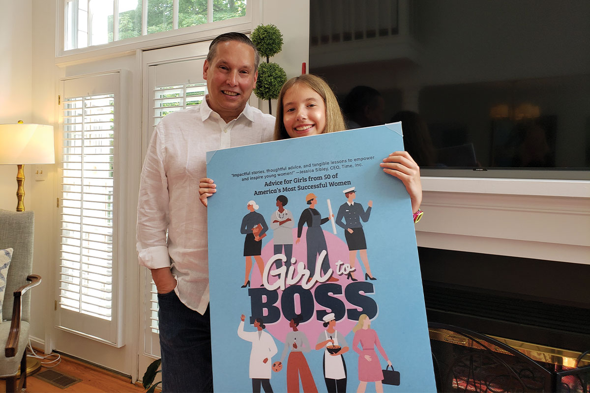 Julia and Paul Brandus with a poster of her book, Girl to Boss