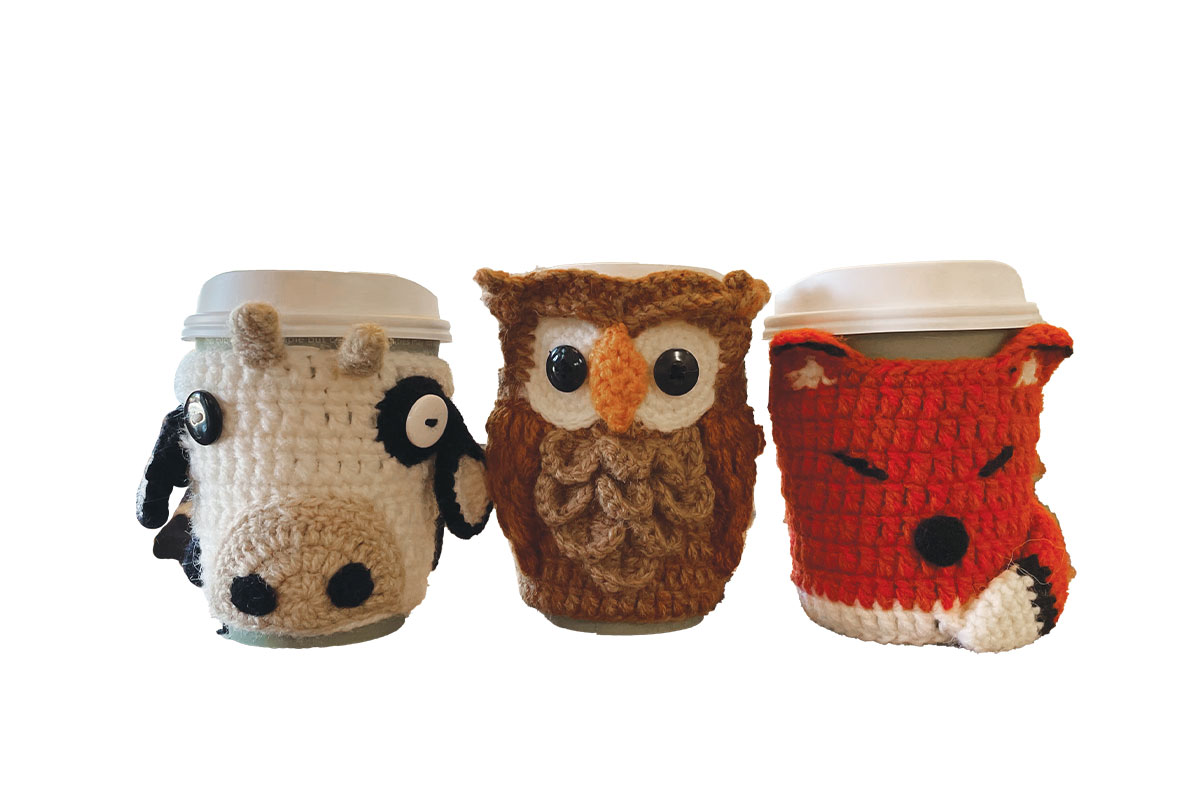 Knit mug cozies that look like a cow, an owl, and a fox