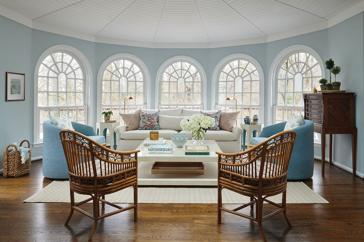 Sunroom with blue walls, high ceilings, and arched windows. 