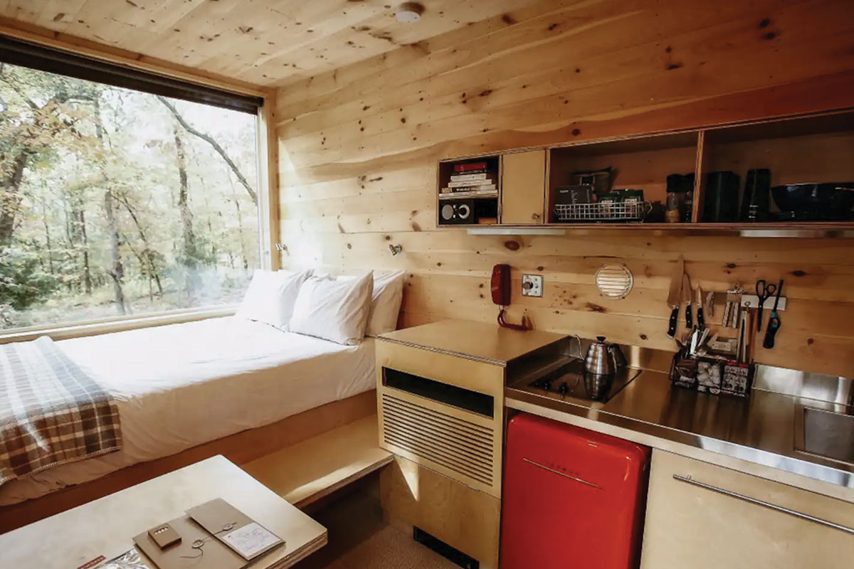 Interior of small wooden cabin with bed and kitchenette