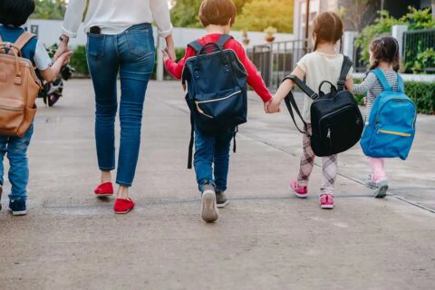 mom holding hands of kids as they walk to school