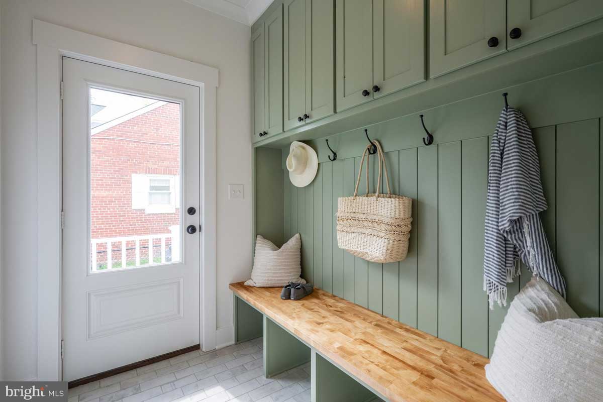 mudroom with green panneled wall and cabinets