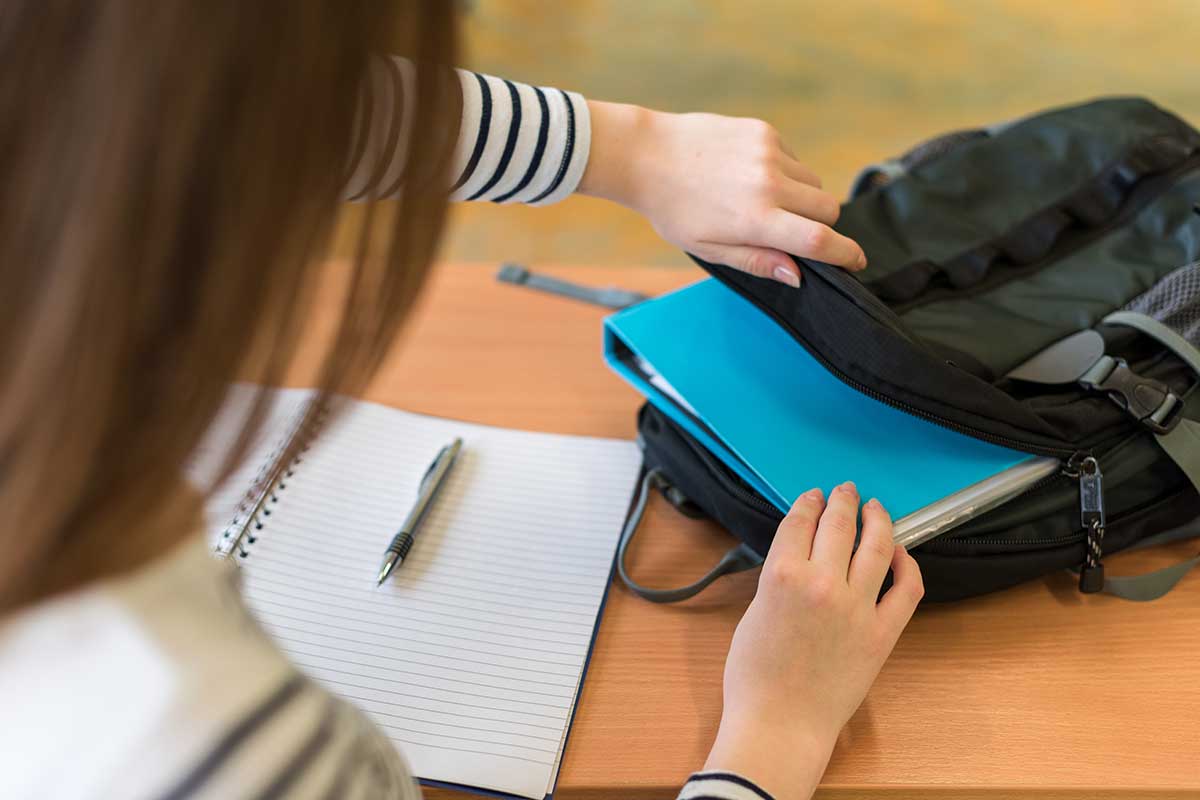 student taking notebook out of bookbag