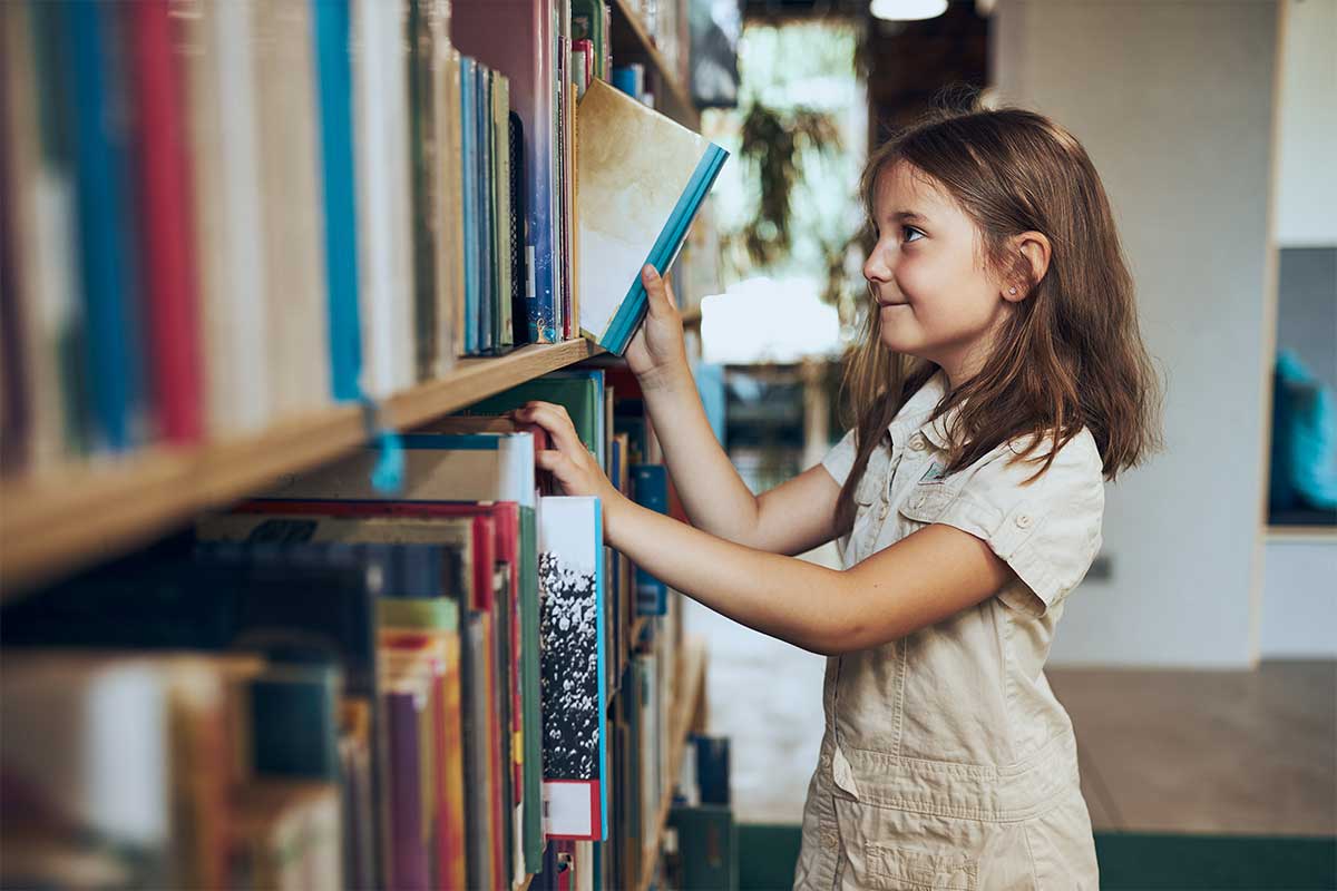 girl picking book from library