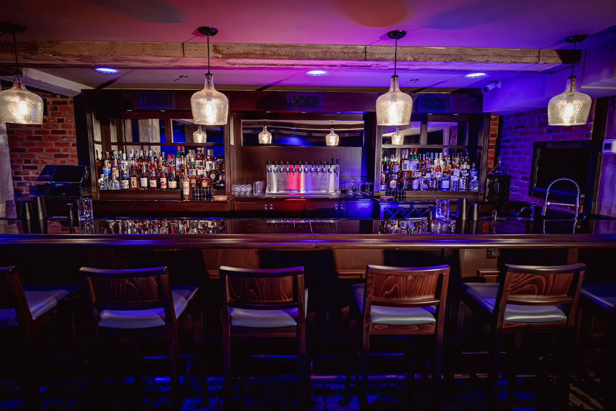 Dark wooden bar area with pink and purple lighting