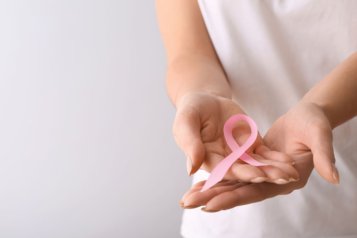 Person holding pink breast cancer ribbon