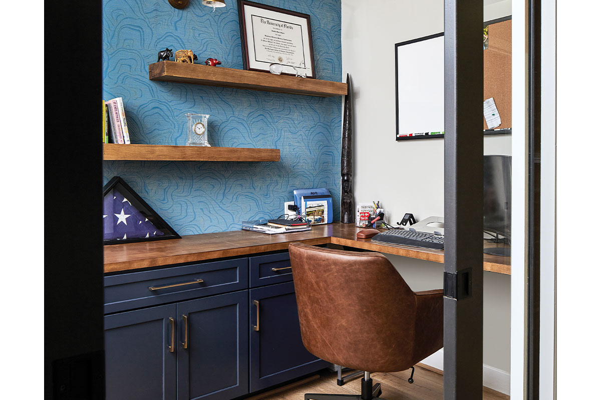 Office area with blue wallpaper and cabinets and brown leather chair