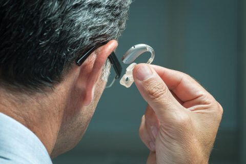 Man putting hearing aid in ear
