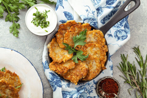 Potato latkes in a pan with parseley, sour cream, and paprika