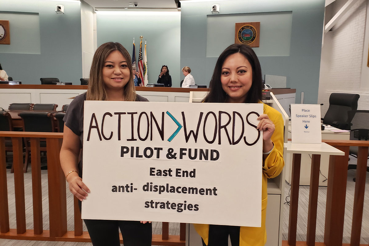 Two women holding a sign that says "Actions > Words"