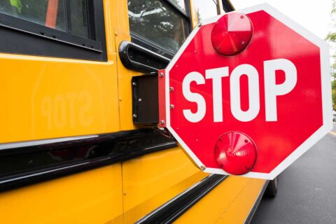 a red stop sign on the side of a yellow school bus