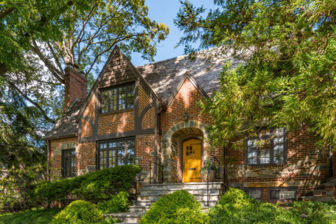 Exterior of home with wood and brick details and yellow door