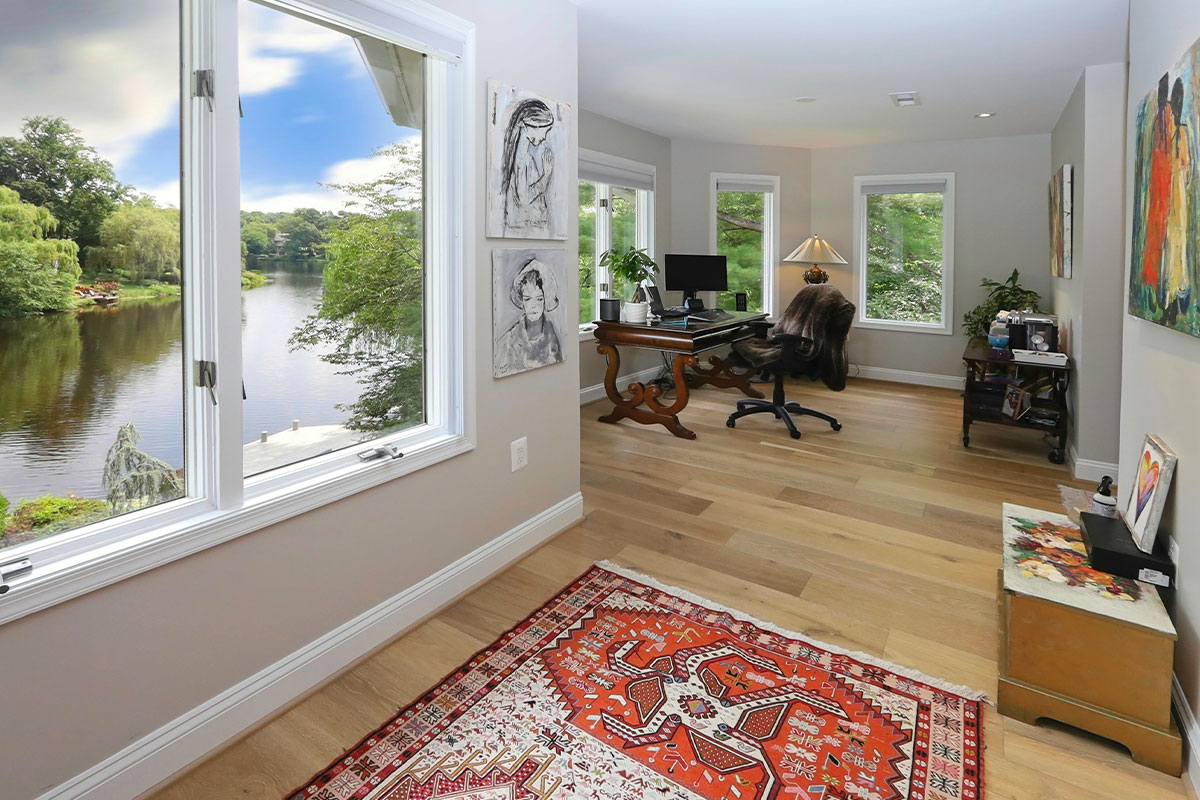 Home office with paintings, wood flooring, and window overlooking lake