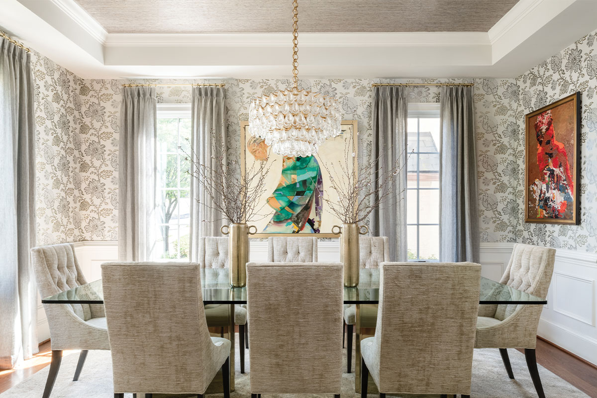 Dining room with crystal chandelier, floral wallpaper, and tan chairs. 