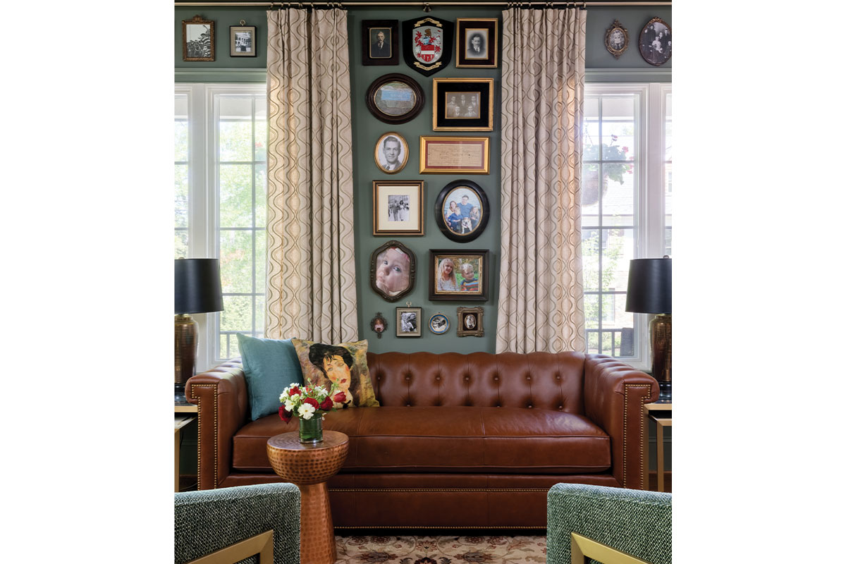 Leather couch under wall full of framed paintings and photographs