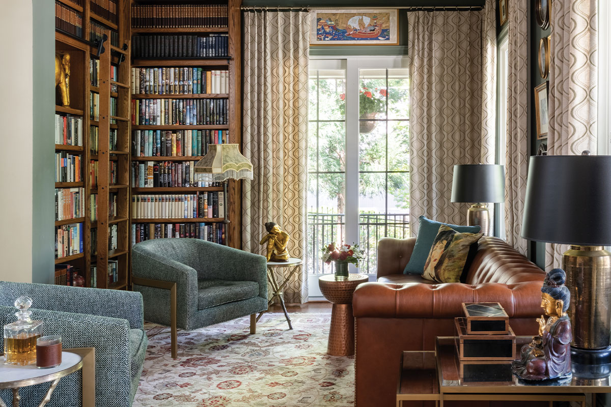 Study with leather couch, blue accent chairs, and built-in bookshelves
