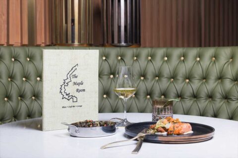 The Maple Room table with plate of food and wine