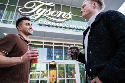 shoppers holding shopping with a twist cups in front of tysons corner center