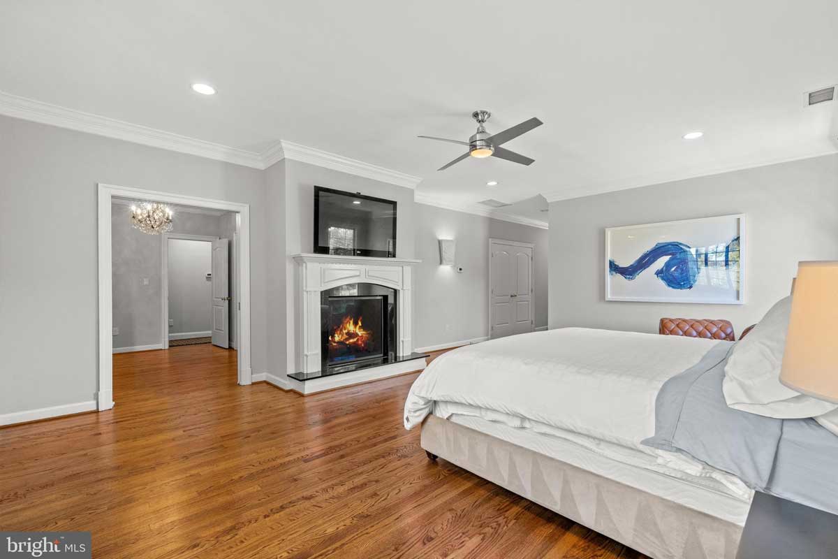 primary bedroom with fireplace and wood floors