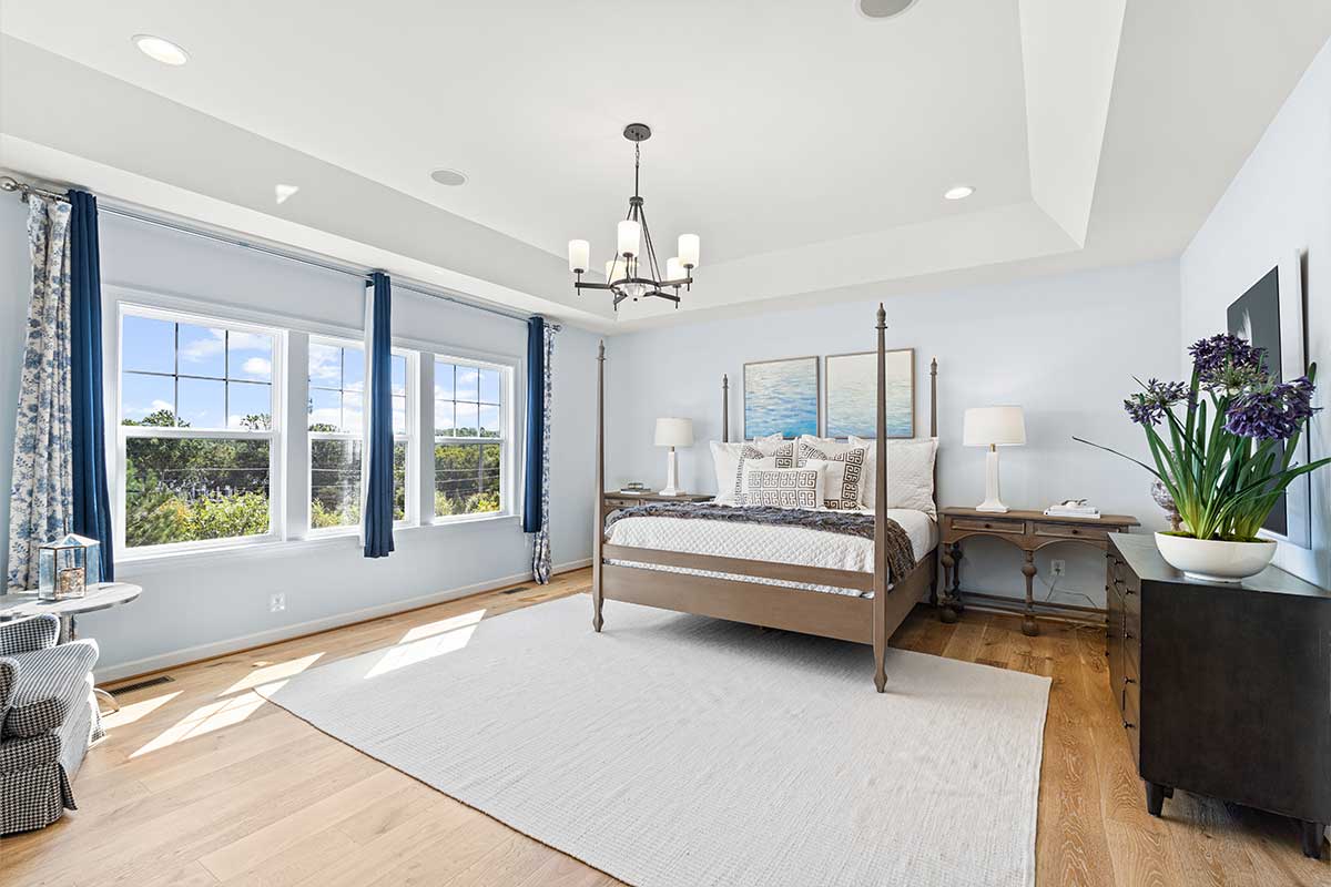 primary bedroom with tray ceiling and wood floors