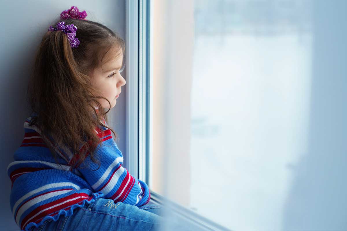 little girl looking out window during winter
